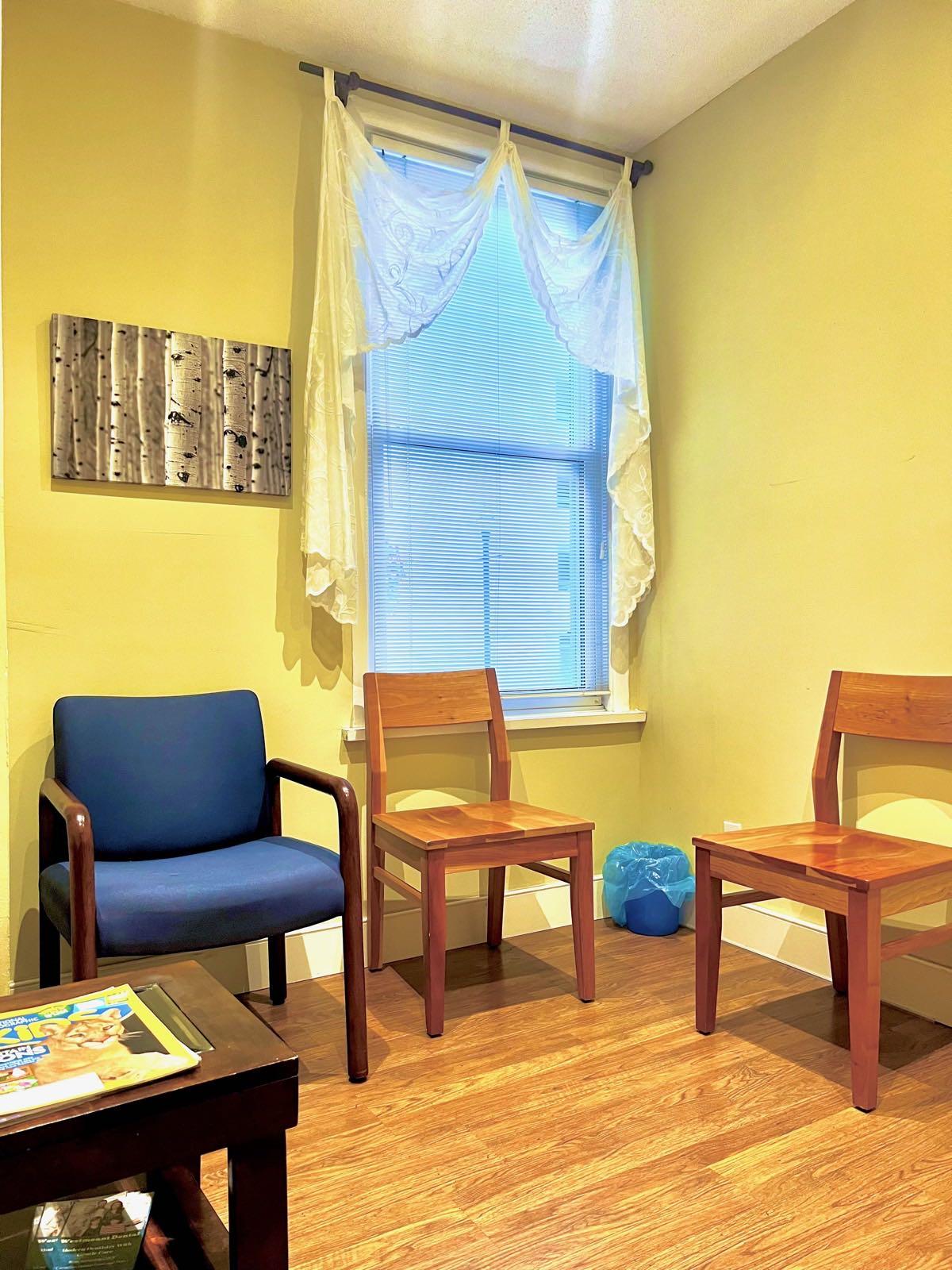 Waiting area with chairs, a coffee table, and a window with blinds